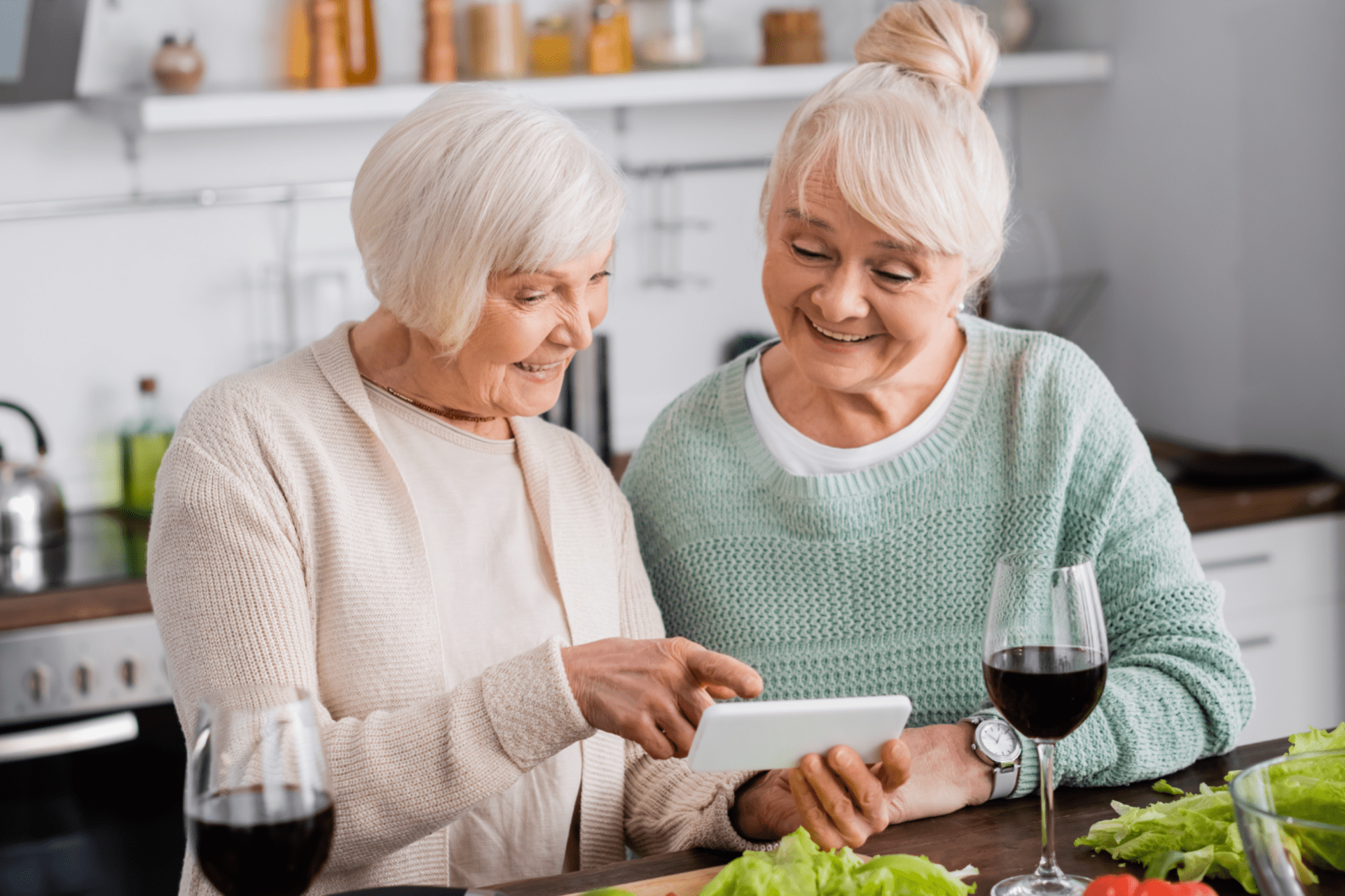 cheerful senior woman pointing with finger at smartphone near retired friend and vegetables on table cheerful senior woman pointing with finger at smartphone near retired friend and vegetables on table